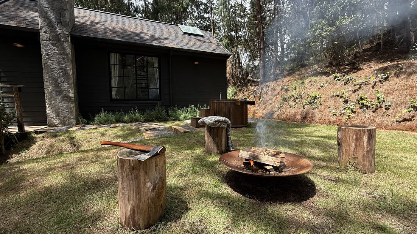 Firepit aceso na área externa, com os bancos de tronco e o ofurô